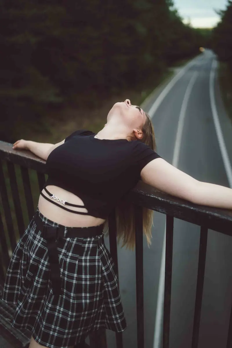Dívka se opírá o zábradlí nad silnicí