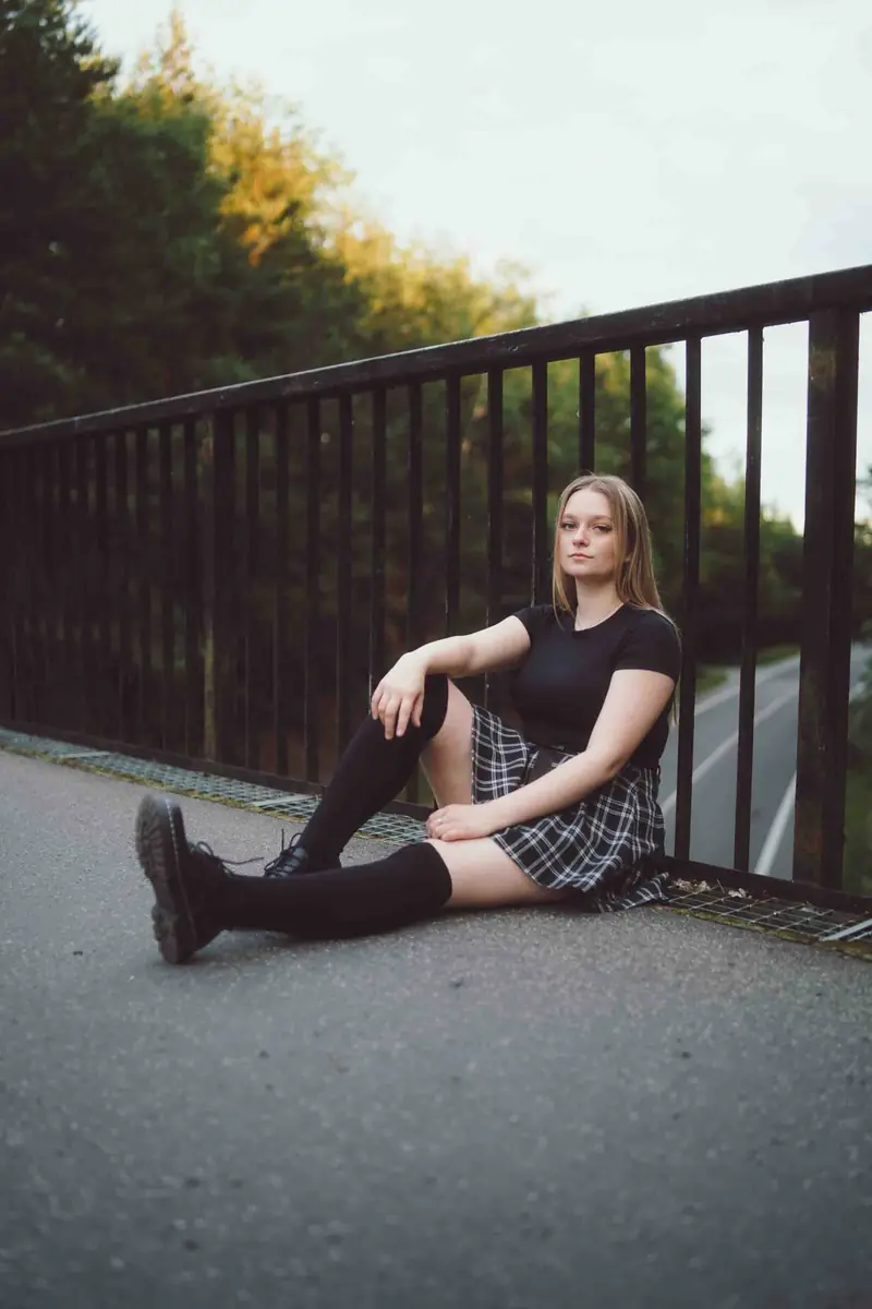 Dívka sedí na mostě u zábradlí
