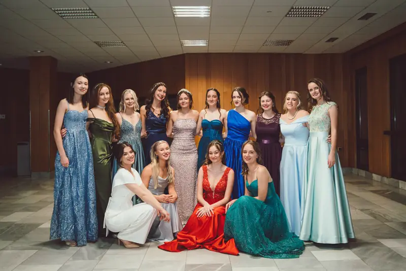 Maturantky ve společenských šatech na skupinové fotce