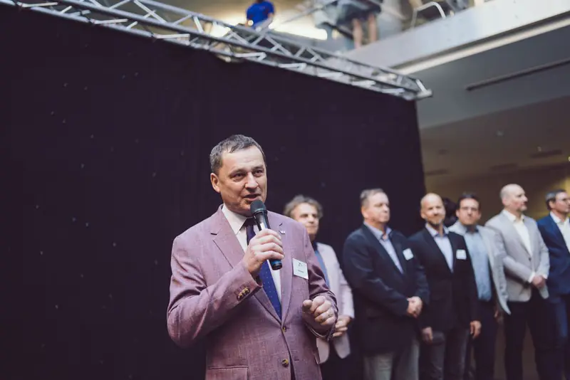 Řečník v růžovém saku mluví do mikrofonu