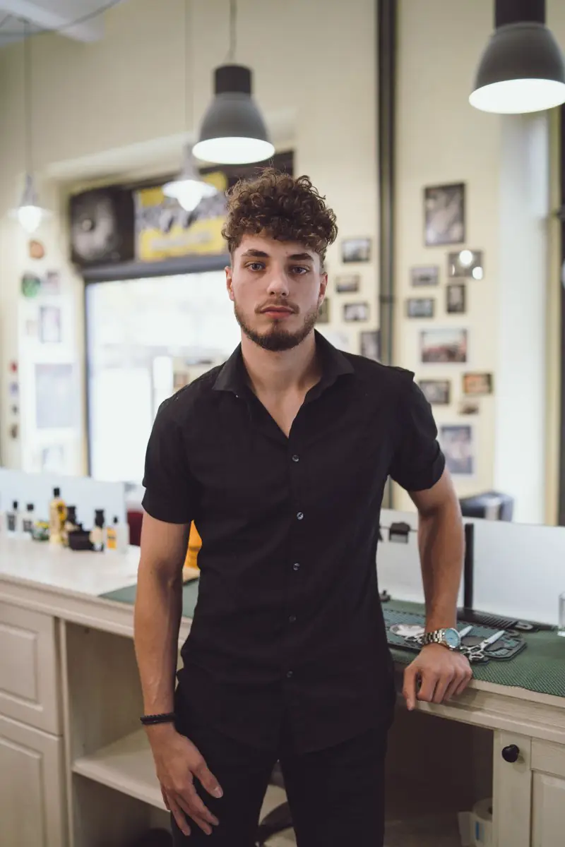 Portrét mladého muže v černé košili v barbershopu
