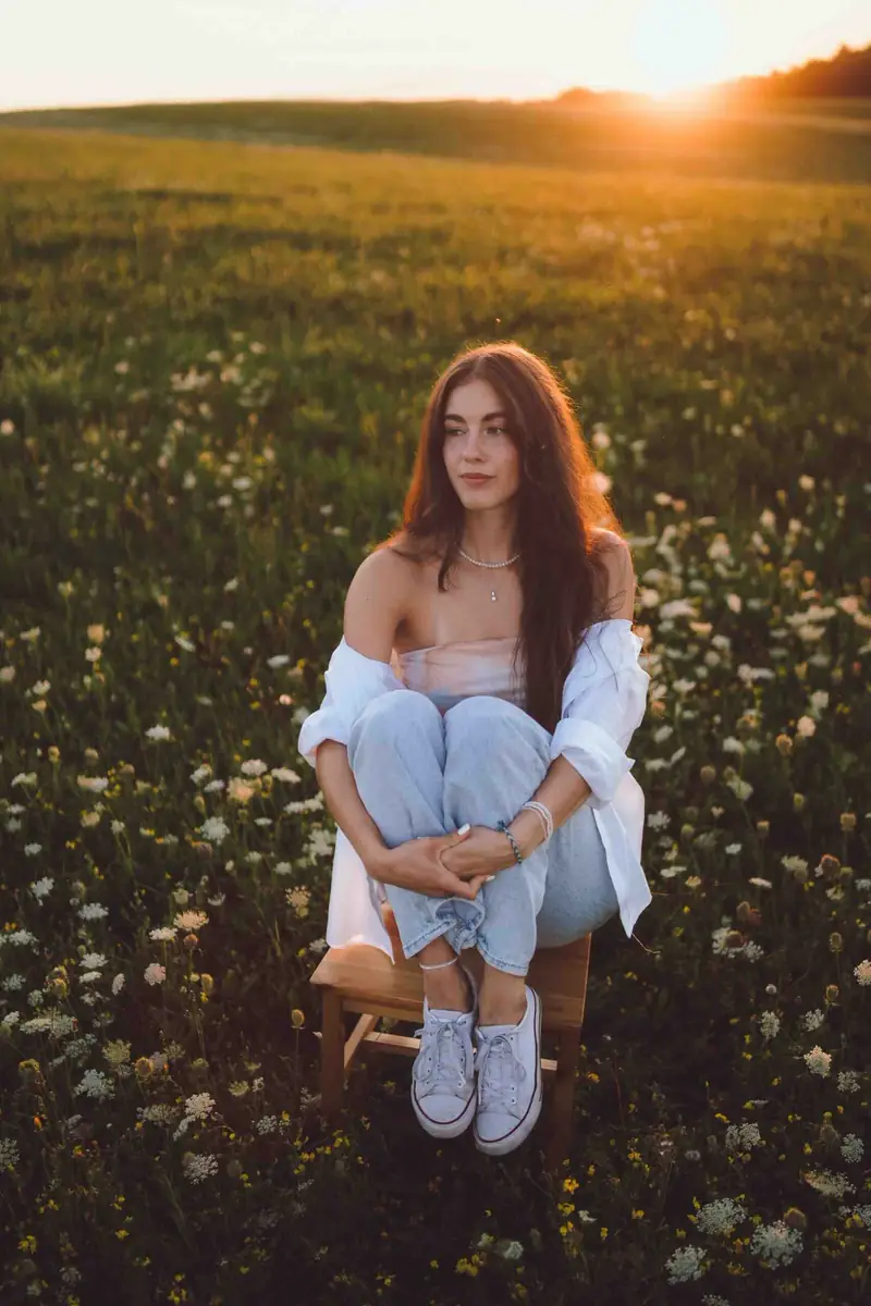 Dívka sedí na židli uprostřed louky