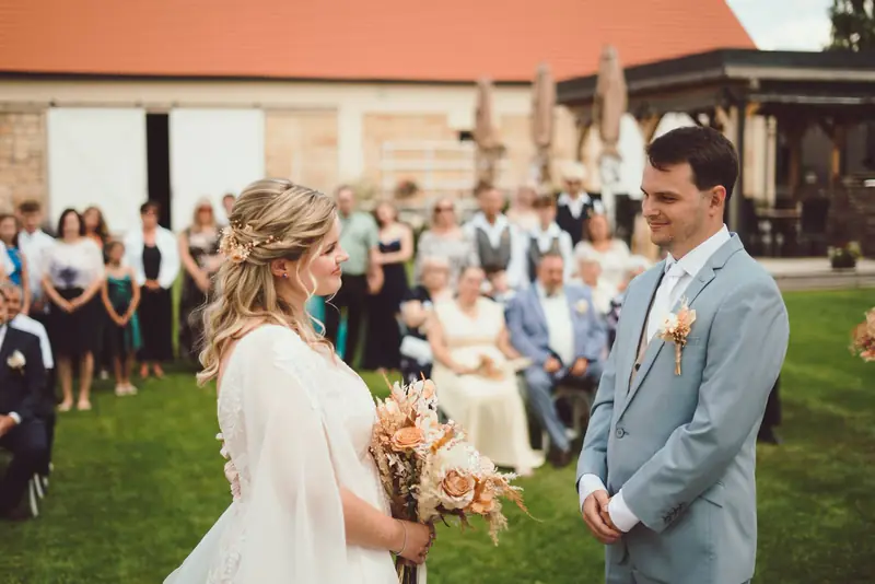 Nevěsta a ženich si hledí do očí při obřadu na zahradě
