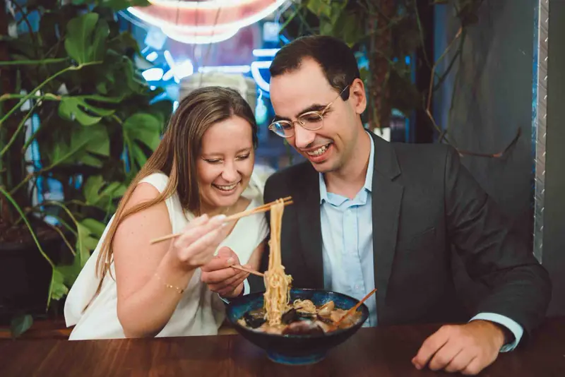 Pár se směje u misky ramenu v restauraci