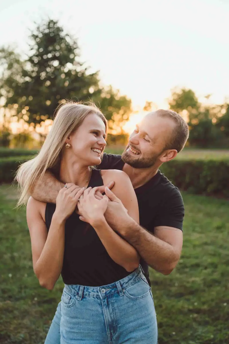Partner objímá partnerku zezadu v parku