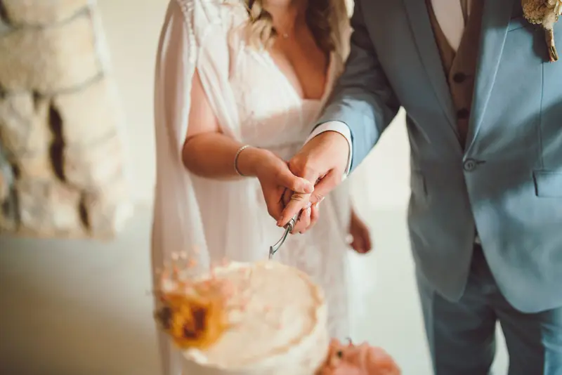 Detail nevěsty a ženicha při krájení dortu