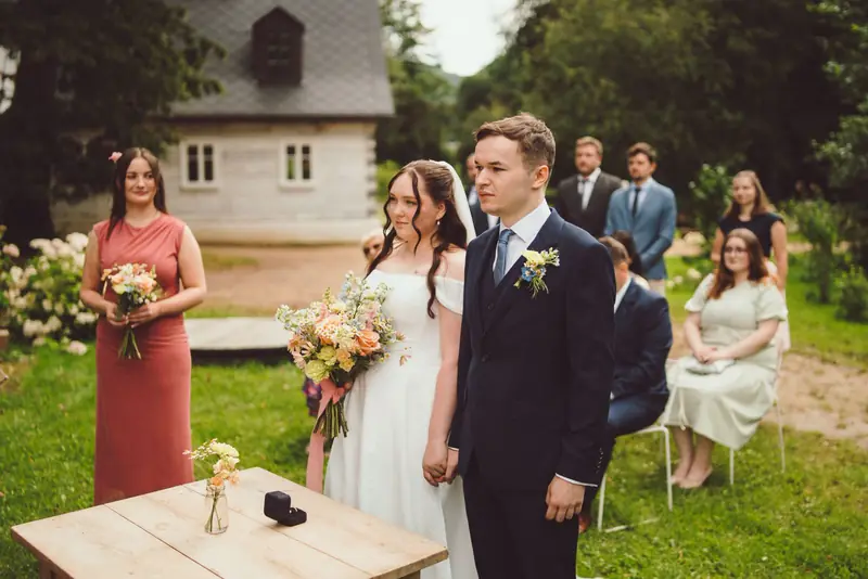 Novomanželé se svatebčany při obřadu v zahradě
