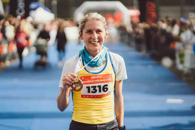 Běžkyně s medailí v cíli půlmaratonu