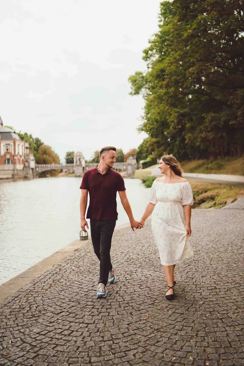 Pár kráčí za ruce po dlážděném nábřeží