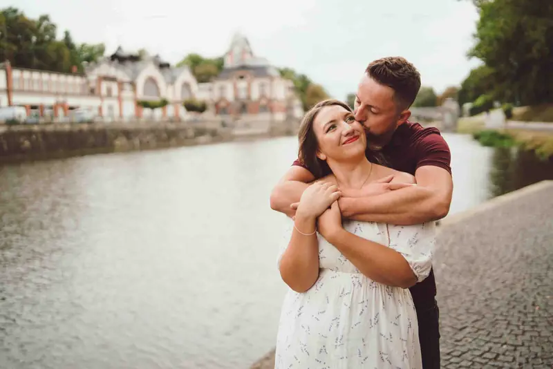 Partner objímá partnerku zezadu u řeky