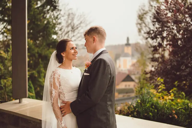 Nevěsta a ženich se smějí na terase s výhledem na město
