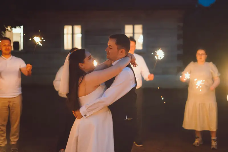 Novomanželé tančí s prskavkami venku po setmění