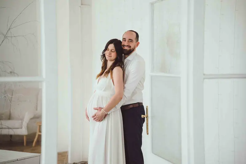 Těhotná žena s partnerem v bílém ateliéru