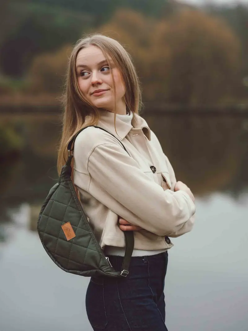 Modelka s prošívanou taškou přes rameno u vody
