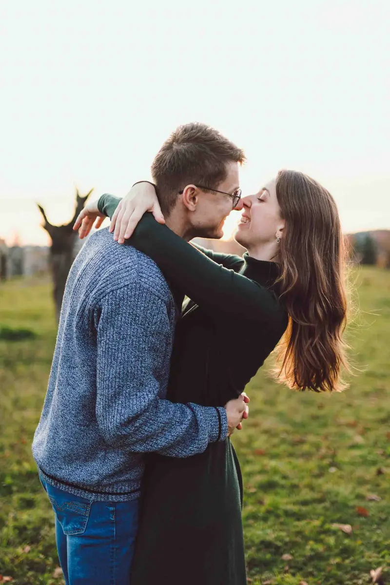Pár se líbá na louce při západu slunce